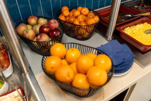 four baskets of oranges and apples on a counter at Travelodge Barcelona Poblenou in Barcelona