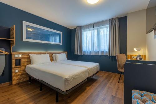 a bedroom with a bed in a room with blue walls at Travelodge Barcelona Poblenou in Barcelona