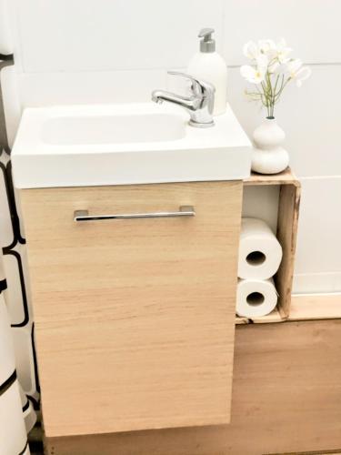 La salle de bains est pourvue d'un lavabo et d'un comptoir blanc. dans l'établissement Le cocon du XVII, à Paris