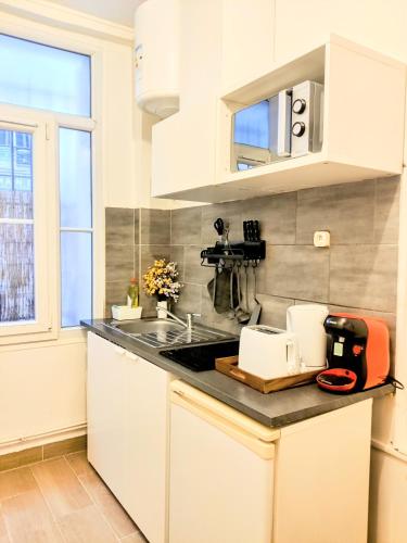 une cuisine avec des armoires blanches et un évier dans l'établissement Le cocon du XVII, à Paris