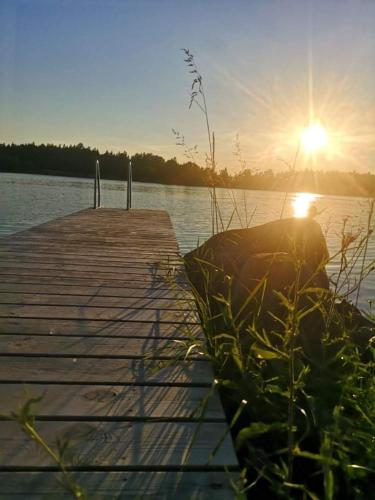 a dock on a lake with the sun setting at Kustvy - En Destination intill Havet in Skärplinge