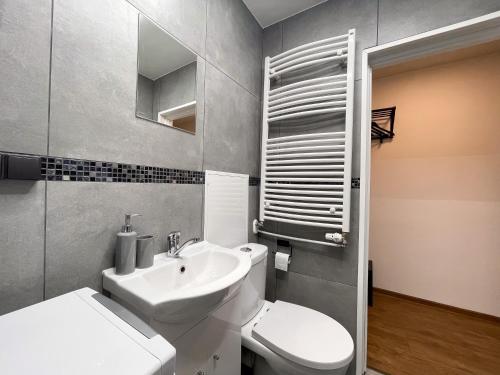 a bathroom with a white toilet and a sink at IG Apartments in Karmėlava