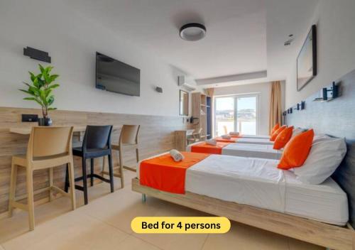 a bedroom with two beds and a table and chairs at Bayside A Apartments in St Julian's