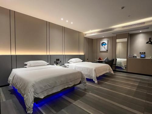 a bedroom with two beds and a desk at Mehood Hotel Leizhou Maodegong Drum City in Zhanjiang