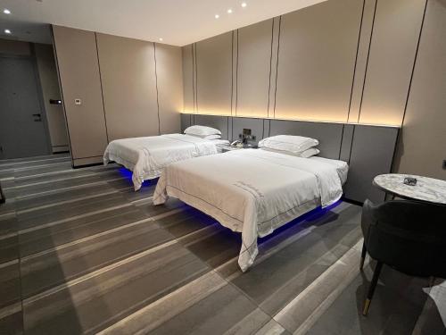two beds in a room with two tables at Mehood Hotel Leizhou Maodegong Drum City in Zhanjiang