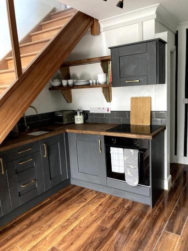 a kitchen with gray cabinets and wooden floors at The Nest in Annascaul