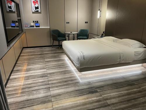 a bedroom with a bed and two chairs and a table at Mehood Hotel Leizhou Maodegong Drum City in Zhanjiang