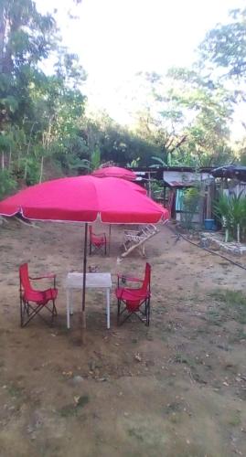 a pink umbrella and four red chairs and a table at Eastdee Camping Ground in Lidlidda