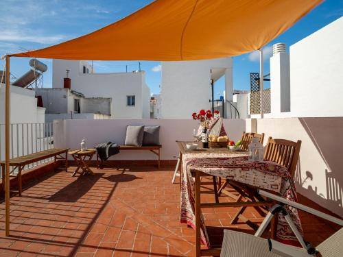 un patio avec une table, des chaises et un parasol dans l'établissement Casa Irene Conil town house in the center, roof terrace with great views, à Conil de la Frontera