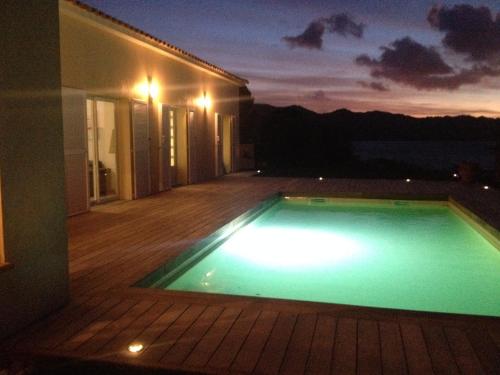 une piscine au milieu d'une maison la nuit dans l'établissement Les Lauriers Roses, à Saint-Florent