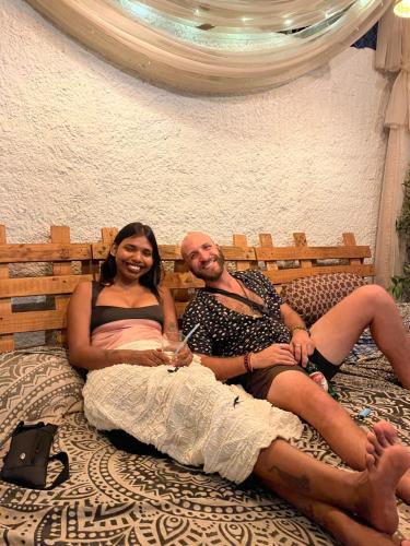 a man and a woman sitting on a bed at HOT - HOUSE OF TRAVELLERS, Vagator in Vagator