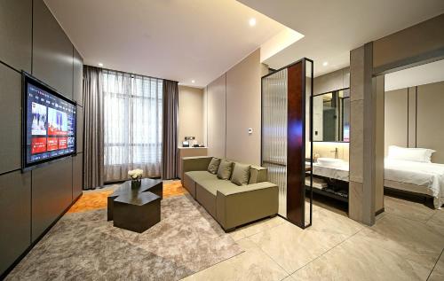 a hotel room with a couch and a bed at Mehood Hotel Leizhou Maodegong Drum City in Zhanjiang