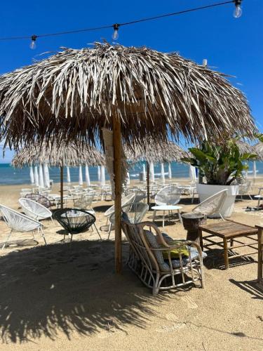 a straw umbrella on a beach with chairs and tables at Casale di Maro in Monte Giberto