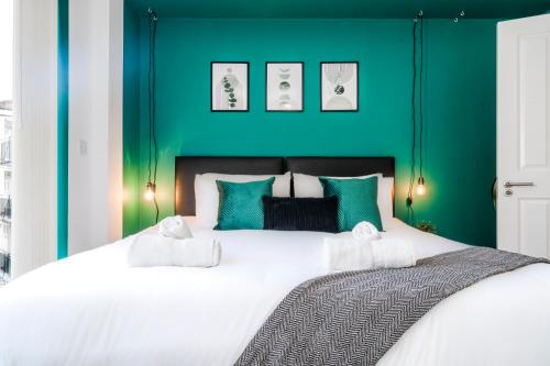 a bedroom with a large bed with a green headboard at Stylish Decor Close to Vibrant O2, Canary Wharf & Isle of Dogs in London