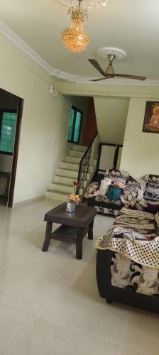 a living room with a couch and a table and stairs at Neelam Gardens in Nashik