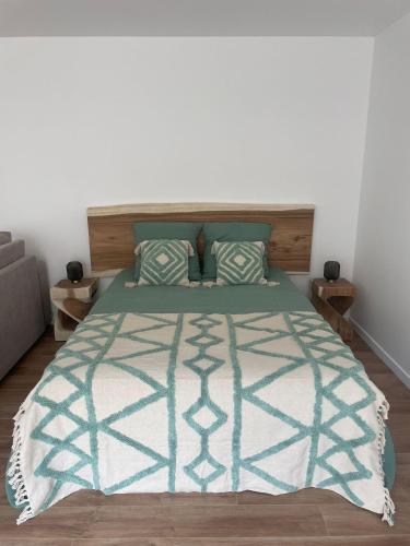 - une chambre avec un lit et une couette verte et blanche dans l'établissement Studio Les Hauteurs de Juziers, à Juziers