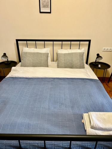 a bed with a blue blanket and two pillows at my house in Tbilisi City