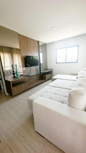 a large room with white furniture and a flat screen tv at Casa e Flat Rio e Praia in Paulista