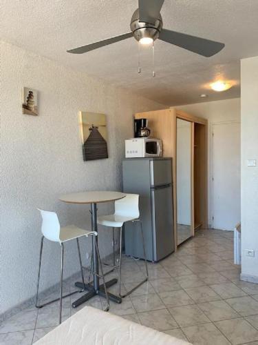 une cuisine avec une table, des chaises et un réfrigérateur dans l'établissement Studio village naturiste Turquoise, au Cap d'Agde