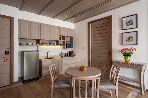 a kitchen with a table and chairs and a refrigerator at Tana Spring Resort Mae Chan in Chiang Rai