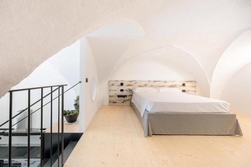 an attic bedroom with a bed and a staircase at Opificio Angiolino Luxury Residence in Melendugno