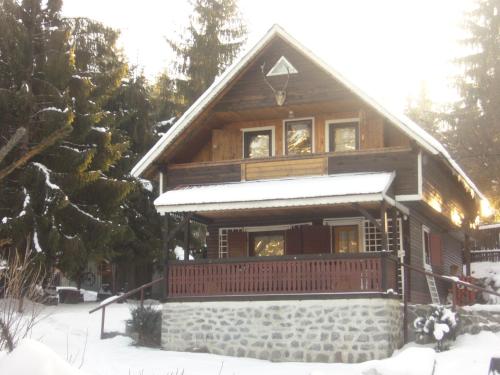 a log cabin with a porch in the snow at Uni-kom forest lodge in Lacu Rosu