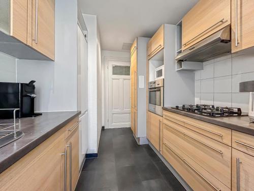 une cuisine avec des armoires en bois et un four à plaques de cuisson dans l'établissement Lumineux & Élégant Centre Strasbourg, à Strasbourg