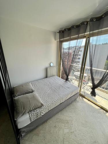 une chambre avec un lit et une grande fenêtre dans l'établissement Studio cosy et lumineux ,Boulevard Gambetta, Nice, à Nice