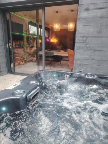 une baignoire jacuzzi dans une chambre avec une table dans l'établissement Station des Plaisirs LOVEROOM, à La Gorgue
