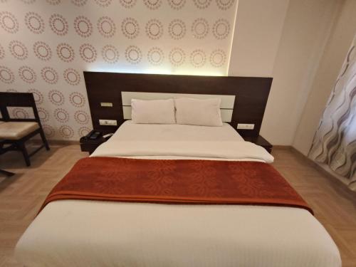 a bedroom with a large bed and a chair at Hotel Vijay Sagar Dombivali in Kalyan