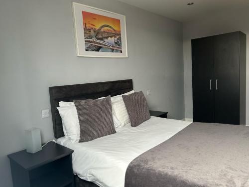 a bedroom with a bed with white sheets and brown pillows at Quayside Apartments Newcastle Upon Tyne in Newcastle upon Tyne