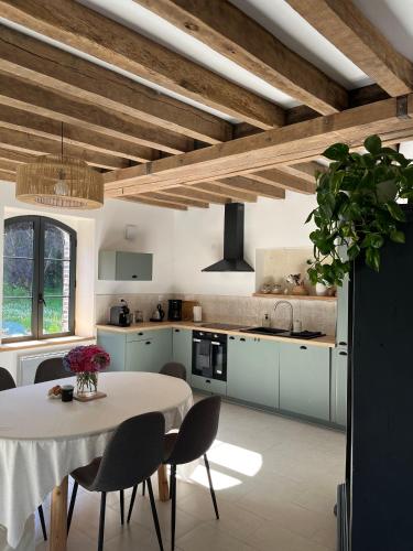 une cuisine avec une table et des chaises blanches ainsi qu'une cuisine avec des armoires bleues dans l'établissement Cottage au cœur du Perche, à Souancé-au-Perche