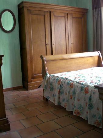 une chambre avec un lit et une armoire en bois dans l'établissement Le clos des oliviers, à Ventabren