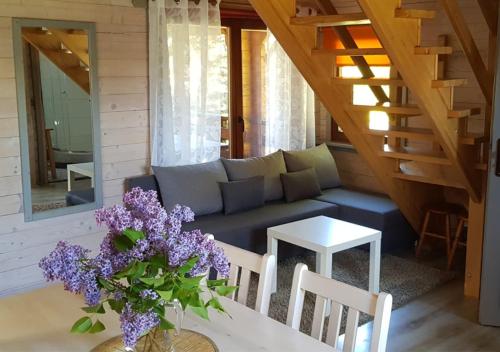 a living room with a couch and a table with purple flowers at Domki na Mazurach - Rybical 65 in Ryn