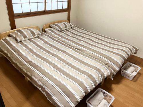 a bed with two pillows and two baskets on the floor at Villa Hineno in Izumi-Sano