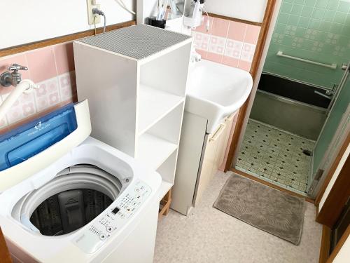 a small bathroom with a washer and dryer at Villa Hineno in Izumi-Sano
