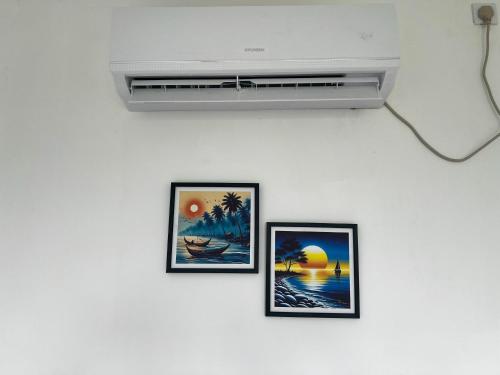 three framed pictures on a white wall with a air conditioner at Meridian Holiday Resort in Ratnapura