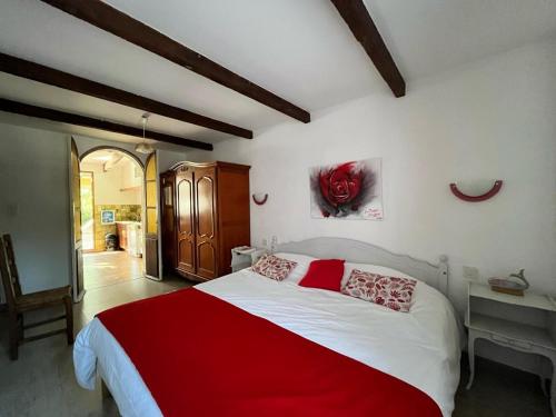 une chambre avec un grand lit avec une couverture rouge dans l'établissement Au jardin de la ferme - roses rouges, à Six-Fours-les-Plages