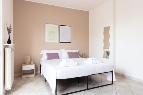 a bedroom with a bed with white sheets and purple pillows at DeHomes - Relax & Business Apartments in Buccinasco