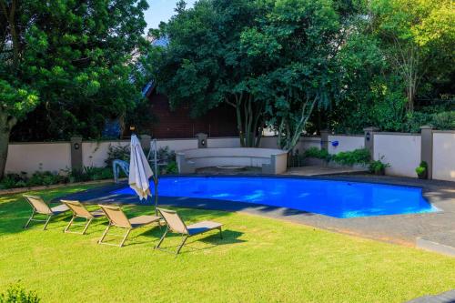 a pool with chairs and an umbrella in a yard at Adinkra Boutique Hotel in Johannesburg