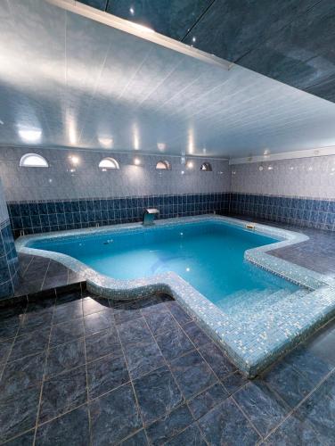 a large swimming pool in a room with a large tub at Ізумруд in Chop