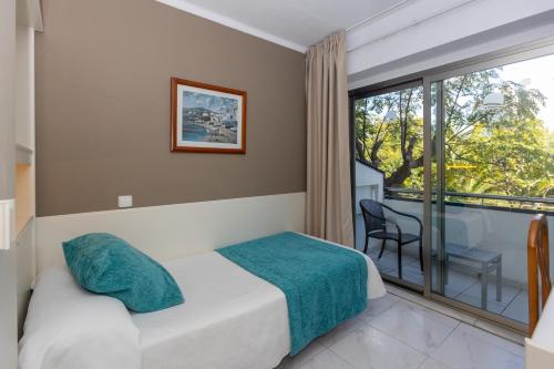 a bedroom with a bed and a large window at Hotel Mariant in S'Illot