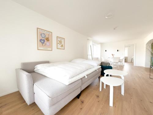 a white living room with a couch and a table at Skyrise Apartments - Stilvoll wohnen, entspannt genießen in Bad Wörishofen