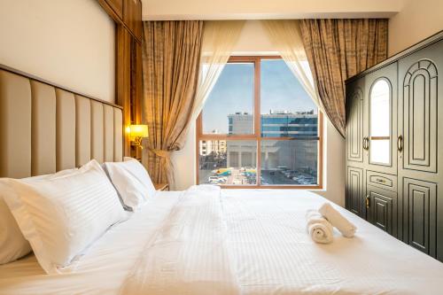 a bedroom with a large white bed with a window at New 1 BR Premium in Dubai