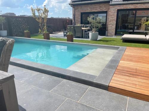 a swimming pool with a wooden deck in a yard at Feelathome De Kust in Middelkerke