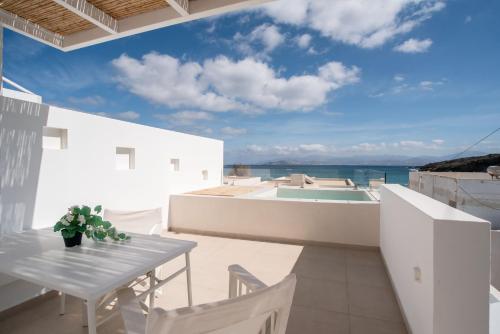 a balcony with a table and chairs and a view of the ocean at Deluxe Maisonette With Private Jacuzzi in Glifades