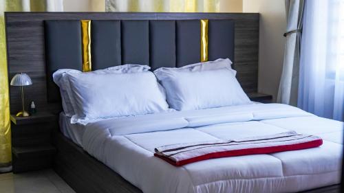 a large bed with white pillows and a red towel on it at Hillside View Apartments Kajjansi in Kajansi