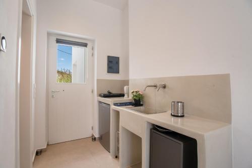 a white kitchen with a counter and a sink at Deluxe Maisonette With Private Jacuzzi in Glifades