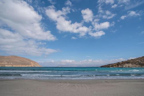 a beach with the ocean and a blue sky and clouds at Deluxe Maisonette With Private Jacuzzi in Glifades