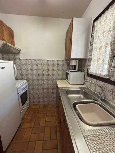 une petite cuisine avec un évier et un micro-ondes dans l'établissement Les Mercadiers, au Lavandou